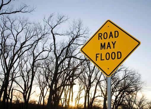 A "road may flood" warning sign beside a road